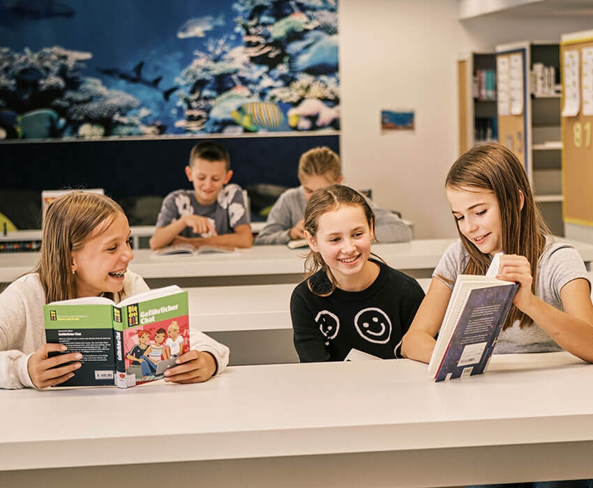 Kinder sitzen in der Bibliothek und lesen Bücher
